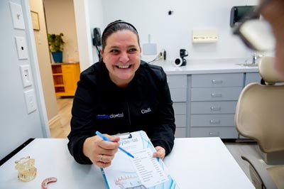 front desk coordinator with new patient paperwork at Clementon Dental