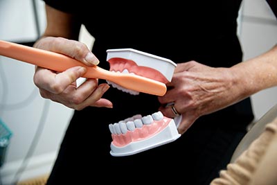 dental hygienist showing how to brush teeth on a mouth model